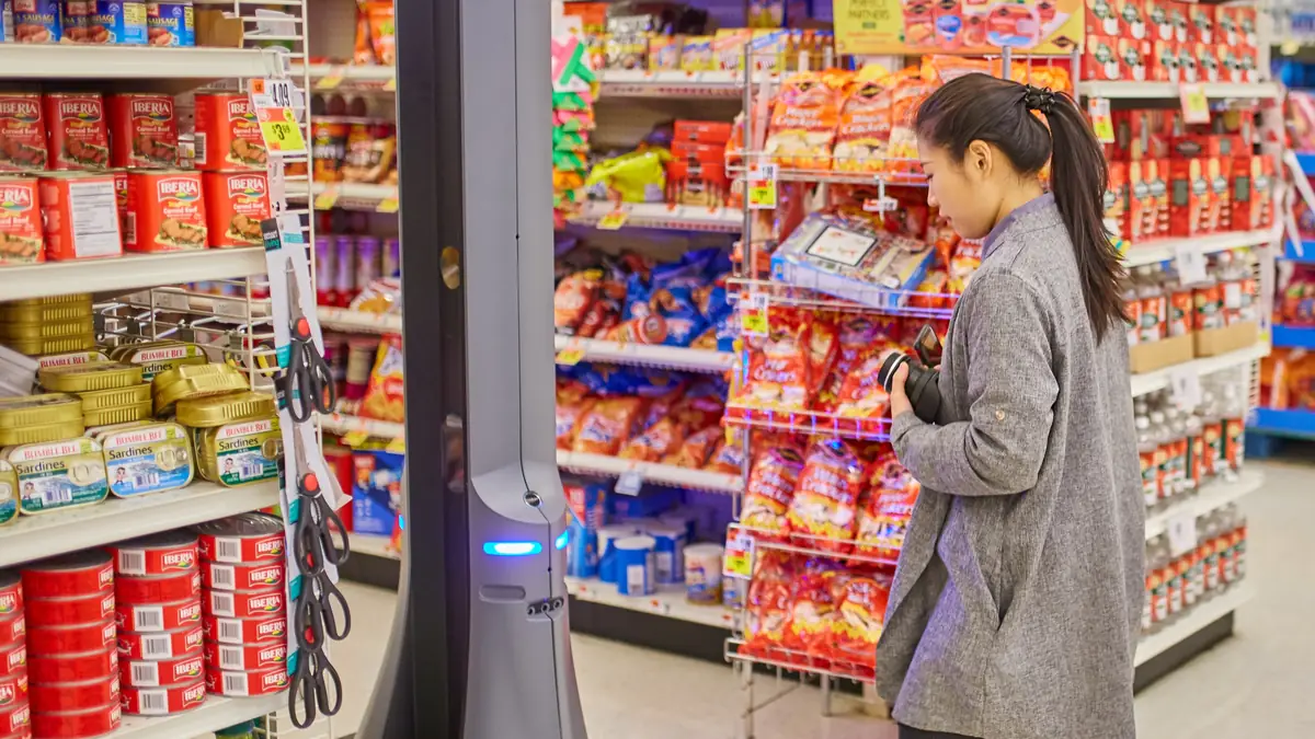 Pessoa diante de um robô de serviço em um corredor de supermercado, representando a convivência entre trabalho humano e automação.